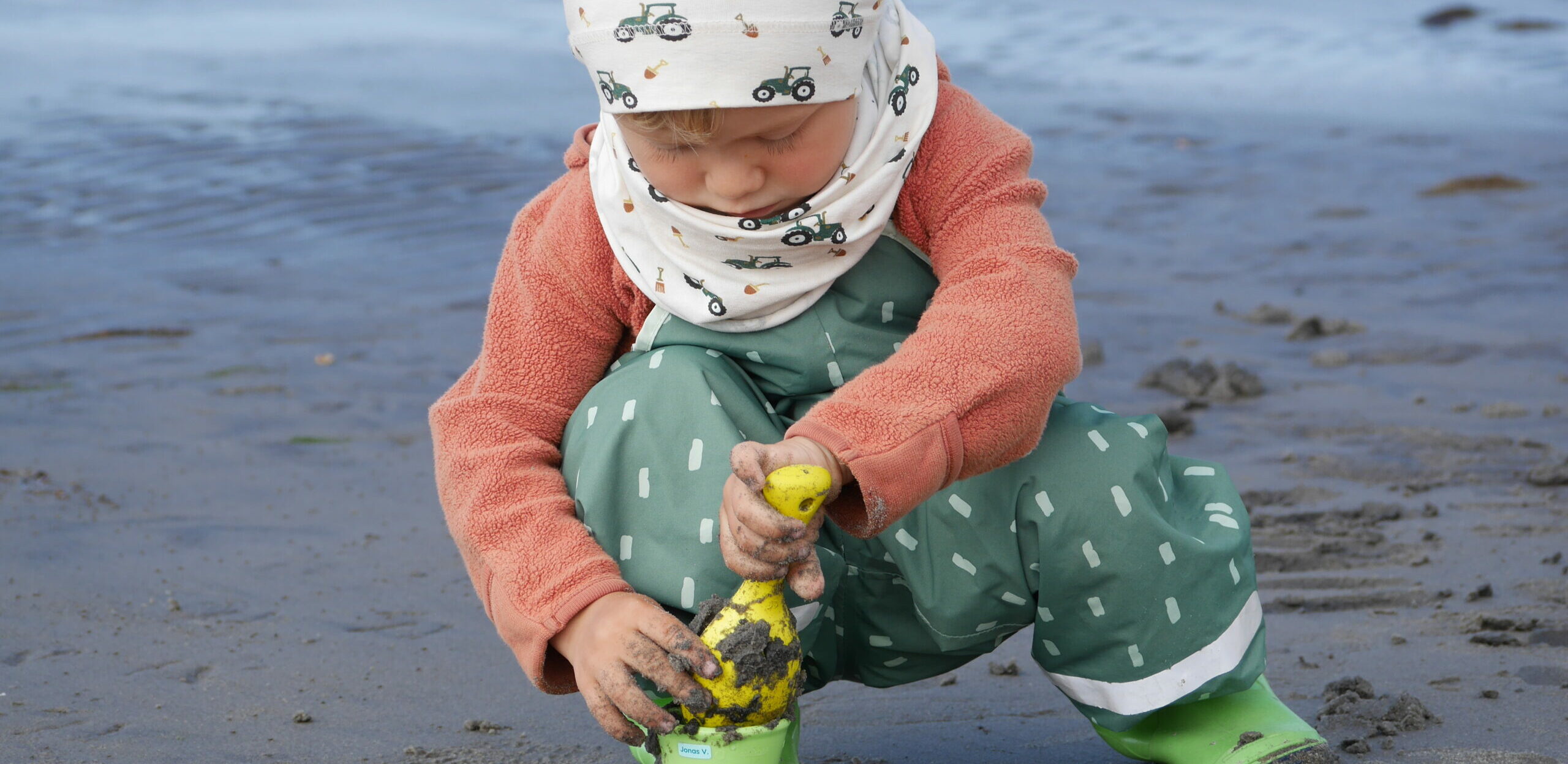 Kind spielt am Strand mit Sandspielsachen