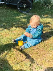 Kleinkind sitzt spielend im Gras