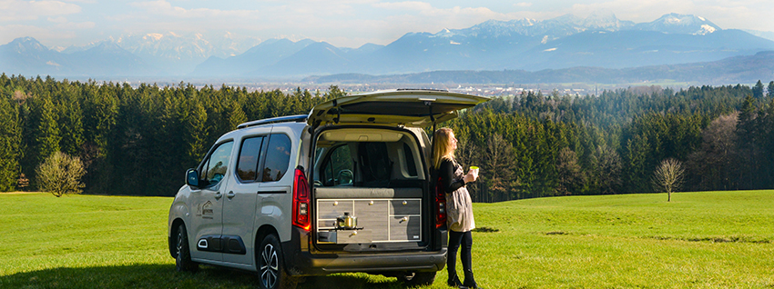 Peugeot Rifter mit Campingküche und Bett in Bergkulisse